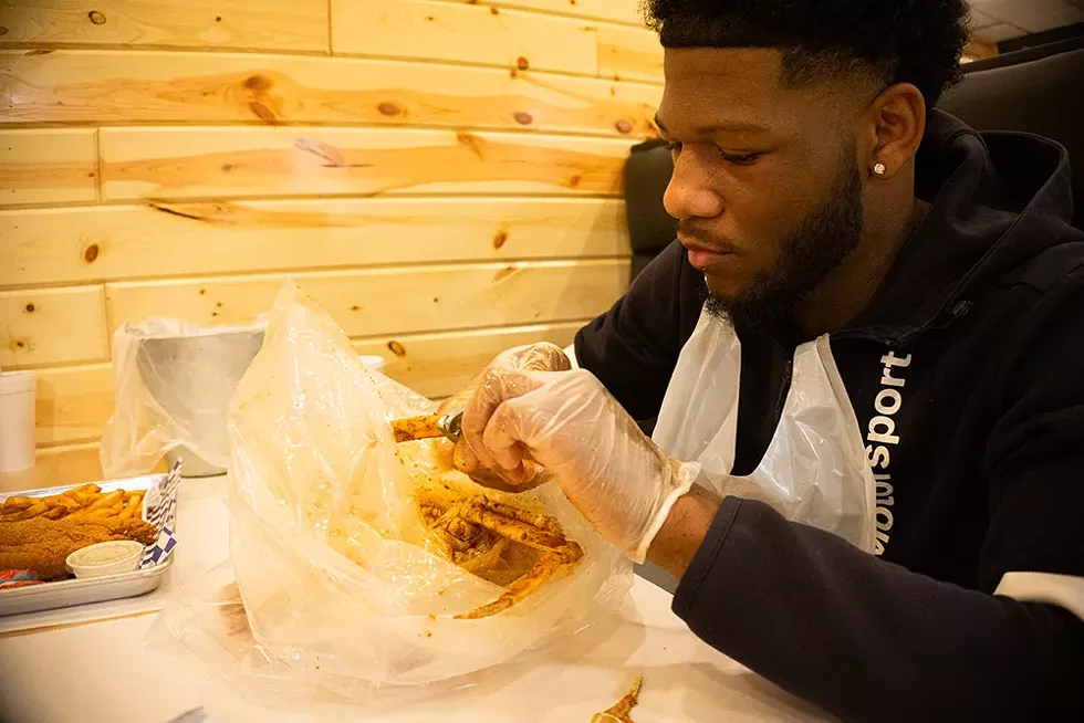 The seafood boil ritual is cartoonishly sloppy and a bit of a carnal affair. A diner digs in at Southfield's Saucey Crab. - SE7ENFIFTEEN