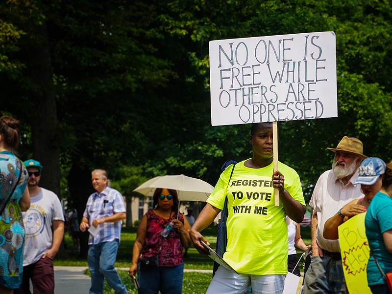 An activist in Detroit holds a protest sign that says "No one is free while others are oppressed." - Stephanie Kenner / Shutterstock.com