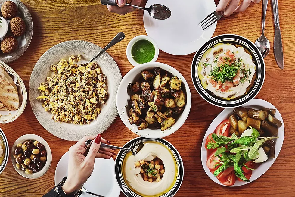 AlTayeb customers feast on a spread of msabbha, falafel, olives, eggs with chunk meat, fool, hummus, spicy potato, jalapeño sauce, and vegetables. - CYBELLE CODISH