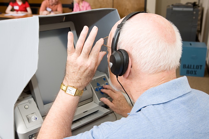 A man uses a touch screen voting machine equipped for the hearing and vision impaired. - Shutterstock