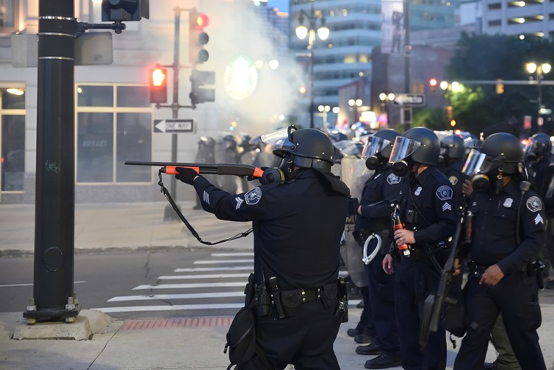 Detroit police officer with non-lethal gun fires at protesters in 2020. - Shutterstock