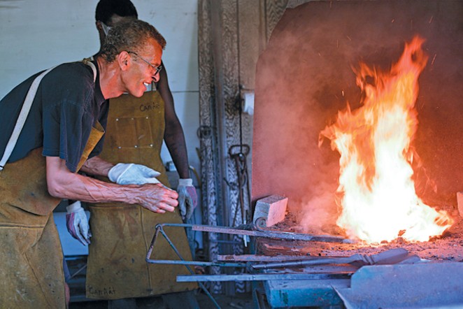Carl Nielbock and his assistant heat metal at Fort Wayne’s 1846 blacksmithing shop. - Justin Rose