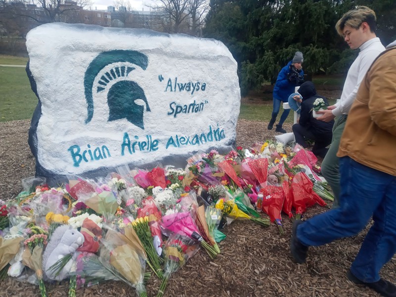 Students drop flowers in front of “The Rock” on MSU’s campus before the school-organized vigil for shooting victims began last week. - Eleanore Catolico