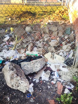 Trash and construction debris on a vacant Velleman-owned lot.