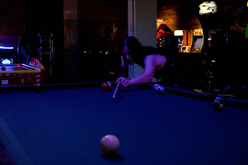 A queer prom attendee plays pool. - Quinn Banks