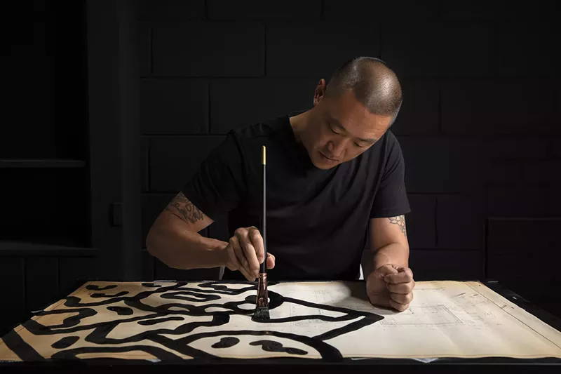 Mike Han working on his Modern Vandalism series, which is painted on blueprints by Detroit architects Minoru Yamasaki and Albert Kahn. - CJ Benninger/Courtesy photo