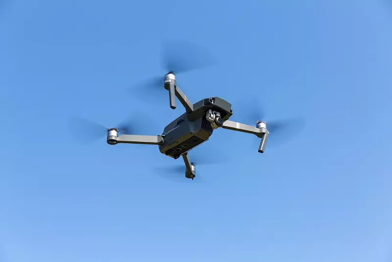 A drone flying against the blue sky. - Shutterstock