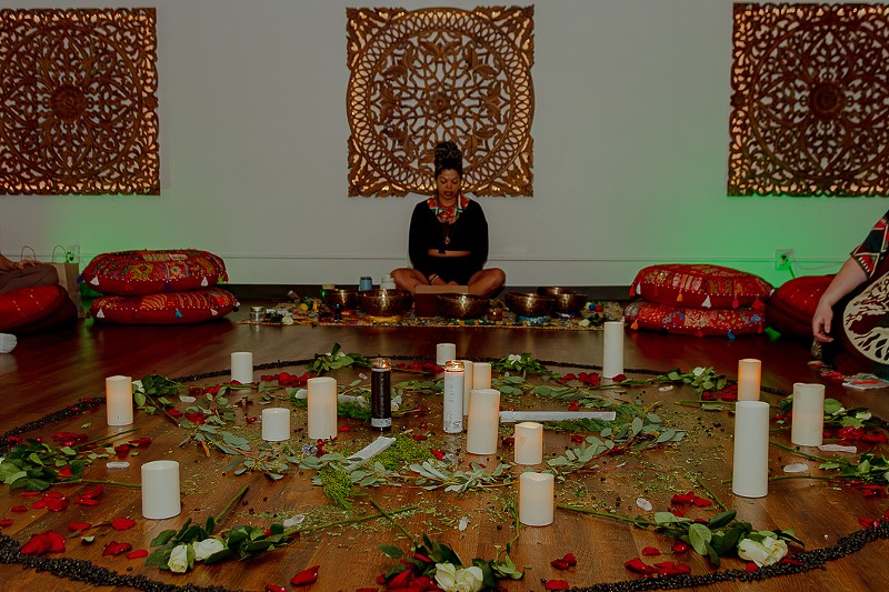 At a January ceremony, an altar of roses, selenite sticks, white candles, and chunks of quartz sits in the middle of a dimly lit room encased by a circle of black beans. - Kendalyn Liebzeit