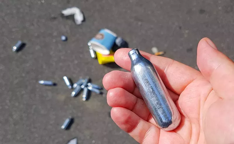 Used cannisters of nitrous oxide litter the ground. - Shutterstock