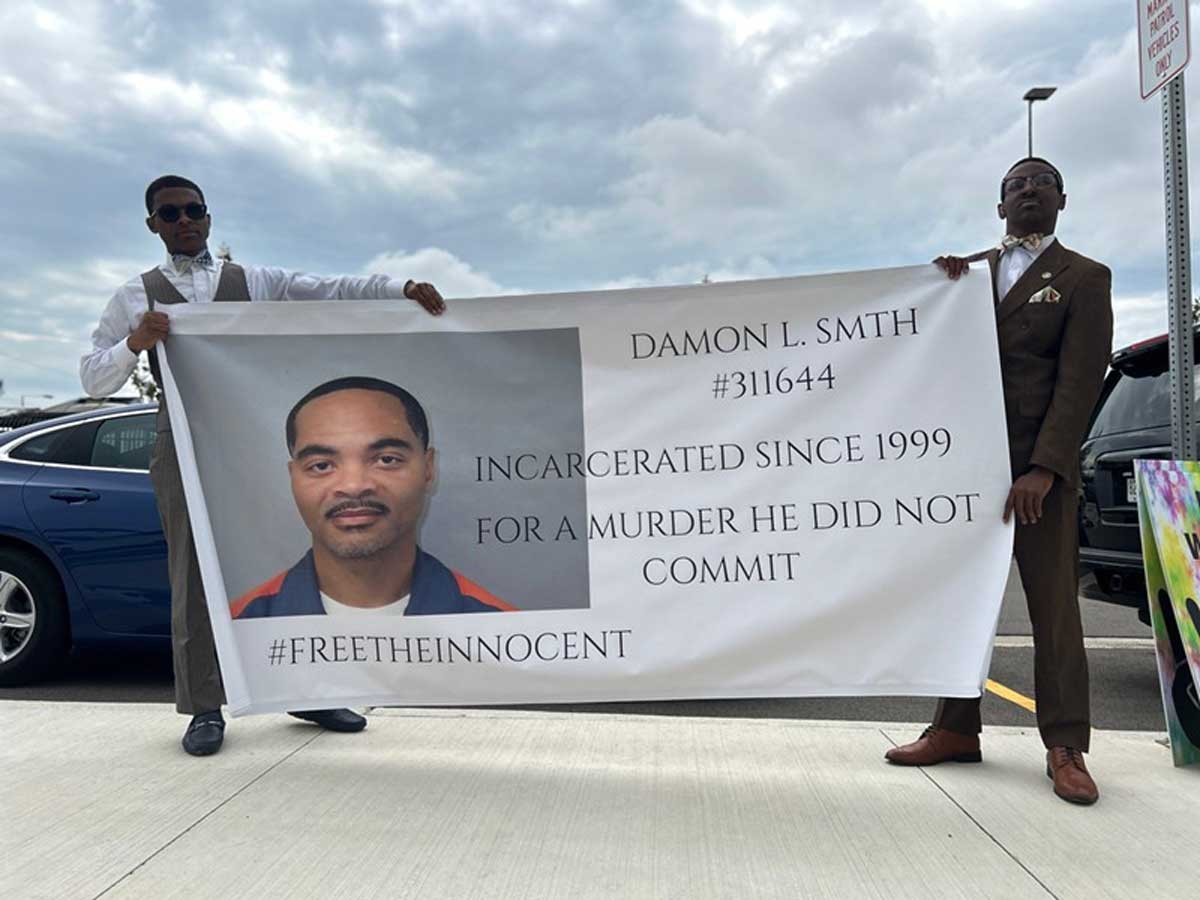 Protesters hold a sign in support of Damon Smith, who has been in prison for 25 years. – Steve Neavling