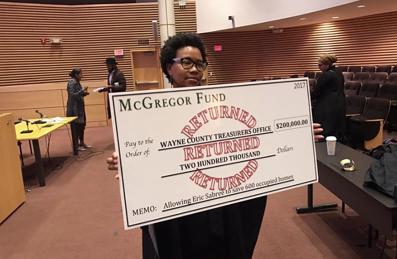 A housing advocate holds a mock "returned" check to the McGregor Foundation. The fund had hoped it could help save 600 occupied homes from the Wayne County tax foreclosure auction this year, but the treasurer rejected the plan, citing its timing. - JERRY PAFFENDORF