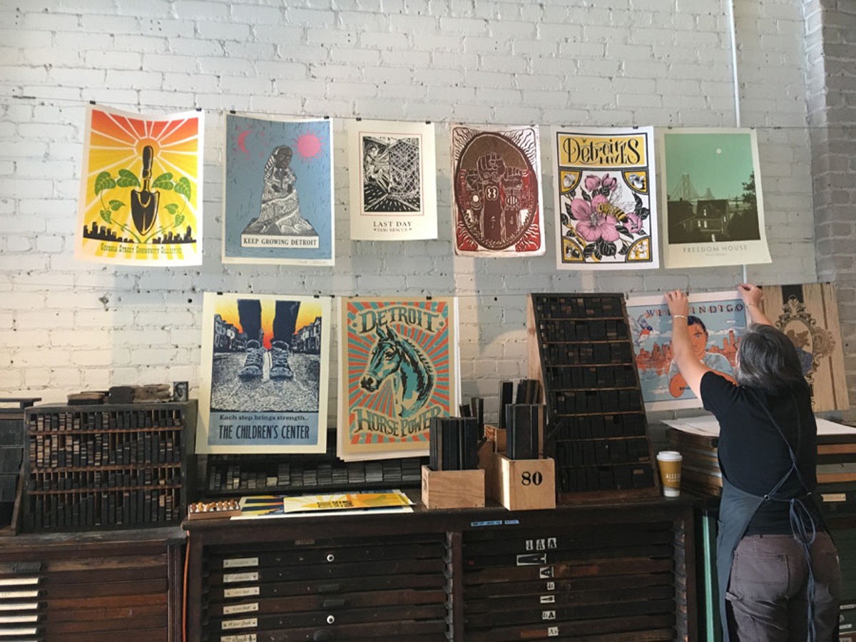 Signal-Return’s Lee Marchalonis hangs up the work from the On Press: Making Visible an Unseen Detroit series.