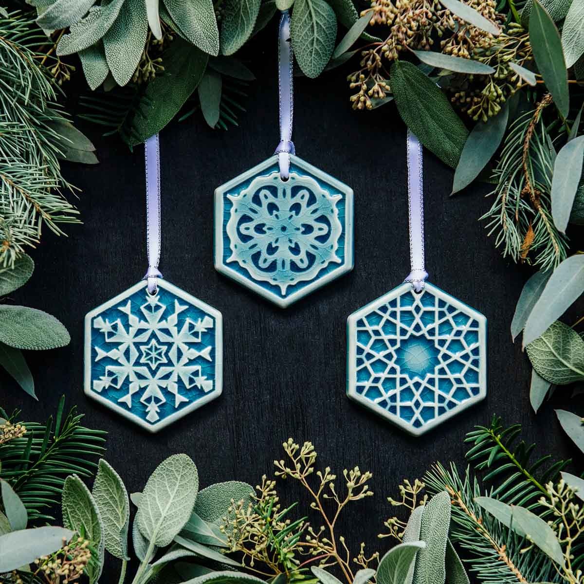 Pewabic's three 2022 Snowflake ornaments hang among holiday greenery.