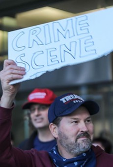 A Trump supporter wielding a sign alleging voter fraud outside of Detroit's TCF Center.