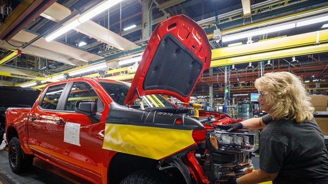 A worker installs a headlight assembly at GM's Chevrolet Silverado and GMC Sierra pickup truck plant.