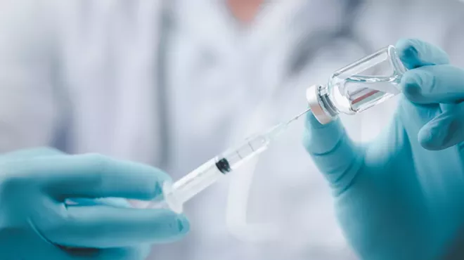 A doctor filling a syringe with a vaccine.