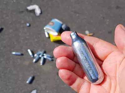 Used cannisters of nitrous oxide litter the ground.