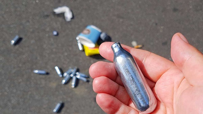 Used cannisters of nitrous oxide litter the ground.