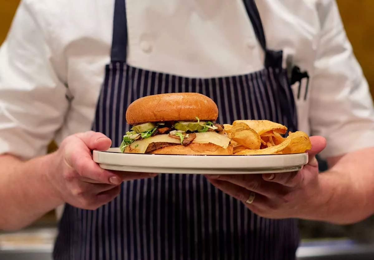 Image: At Hamilton’s, servers wear aprons with the Carhartt logo to commemorate a previous business on the site: a clothing factory owned by Hamilton Carhartt.